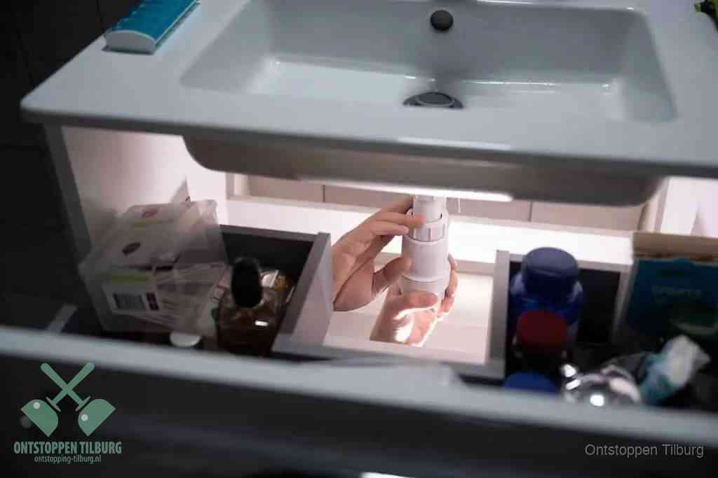 Een pompfles met zeep boven een wastafel, de heet water en afwasmiddel-methode om een vetprop in de afvoer los te maken in Tilburg