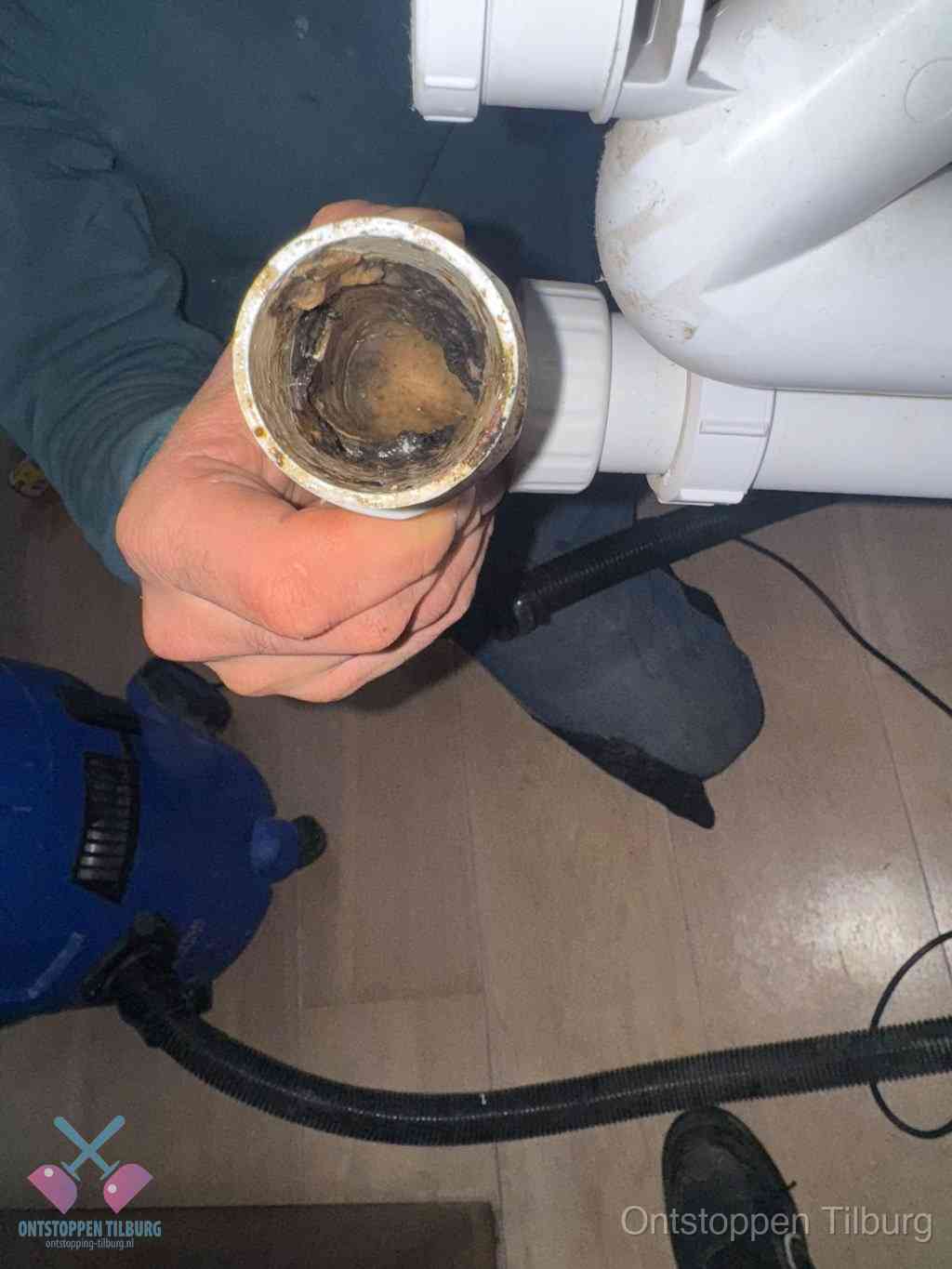 Een losgekoppelde afvoerbuis die van binnen volledig is dichtgeslibd met vet en aanslag, de meest voorkomende oorzaak van een verstopte gootsteen in Tilburg