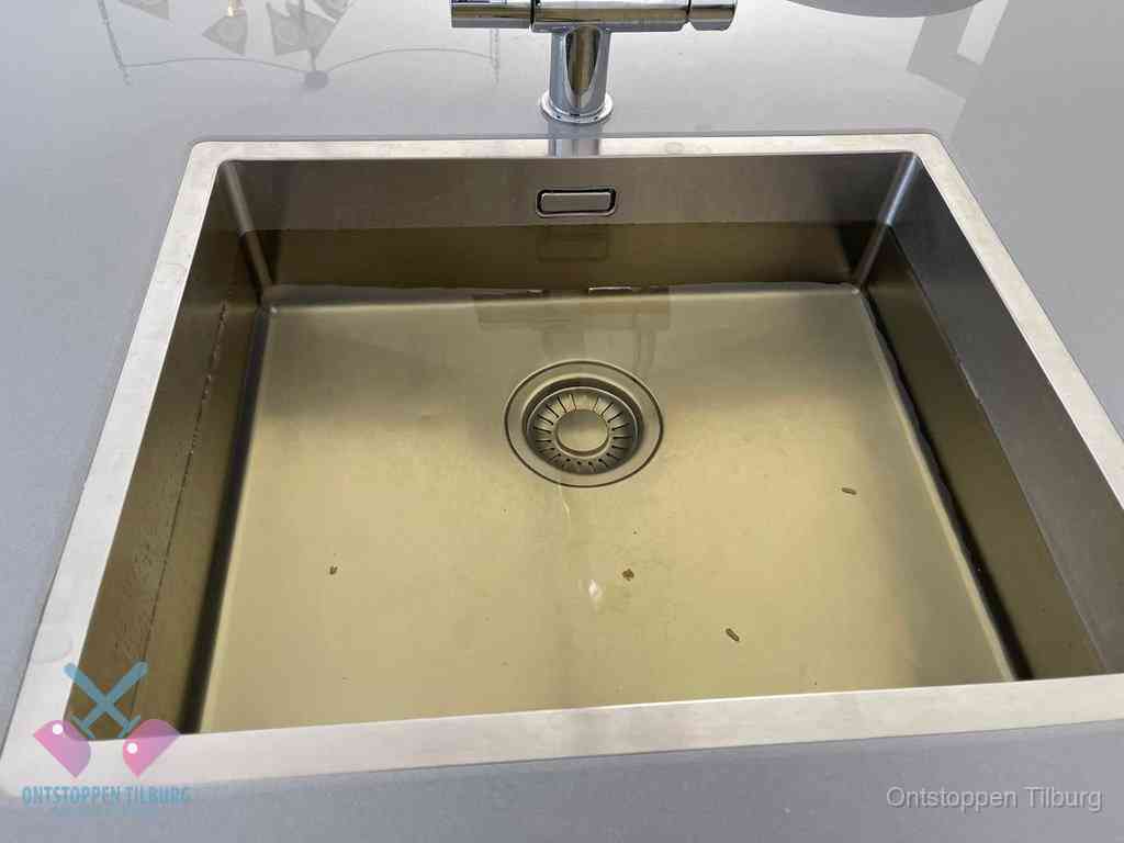 Stilstaand water in een rvs spoelbak dat niet wegloopt, een duidelijk signaal van een gootsteenverstopping in Tilburg