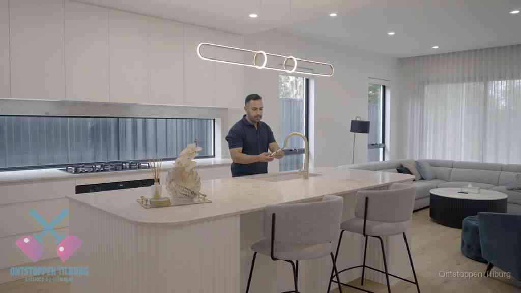 Een bewoner bij de keukenspoelbak die zelf aan de slag gaat met een verstopte gootsteen in Tilburg